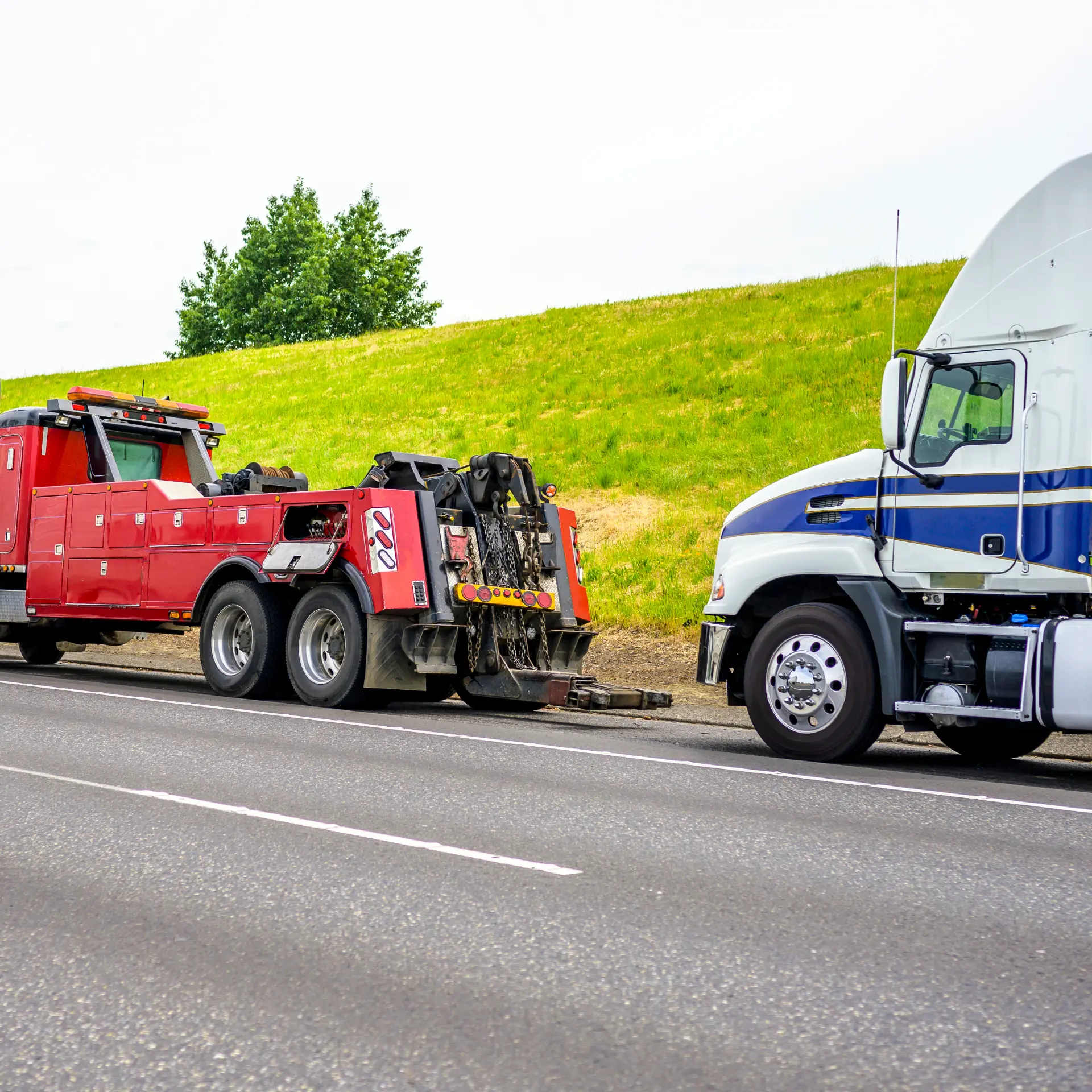 Heavy tow truck alongside a semi truck on the highway